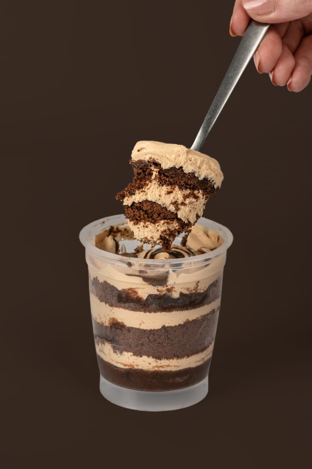 Postre de chocolate en capas con una cucharada, sobre un fondo marrón.