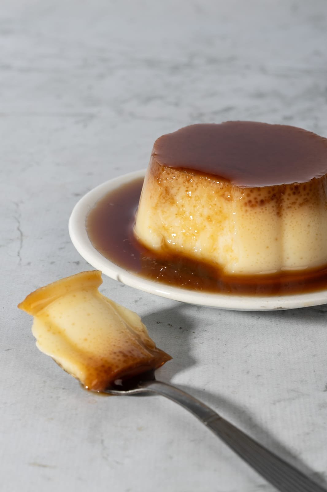 Flan Abuela Ñata con caramelo, servido en un plato y una cucharada lista para disfrutar.